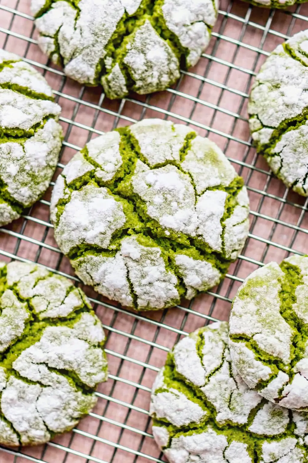 Alt Text: Stack of matcha crinkle cookies with powdered sugar cracks and vibrant green centers.