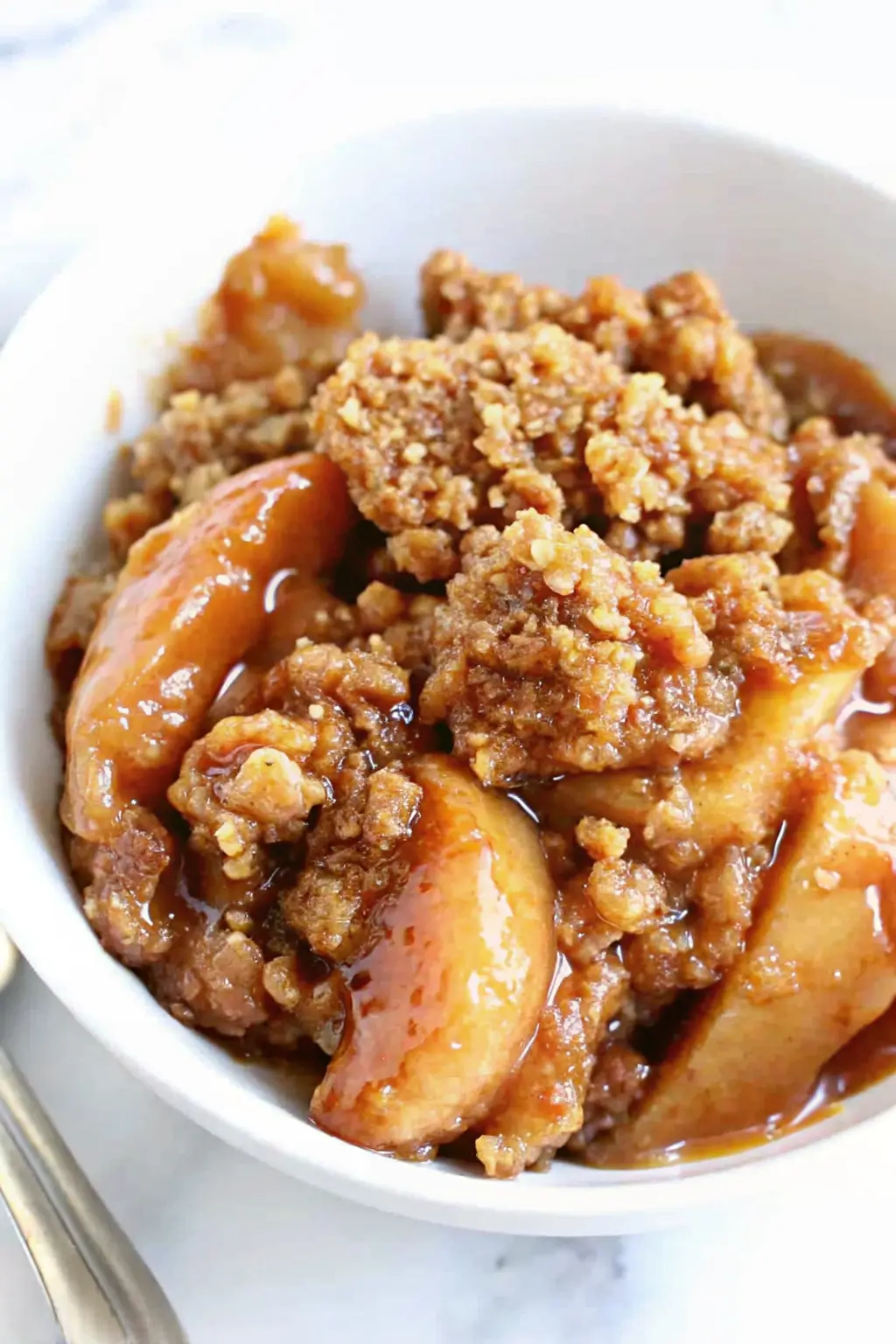 Homemade apple crisp recipe with golden oat topping and baked cinnamon apples in a white baking dish