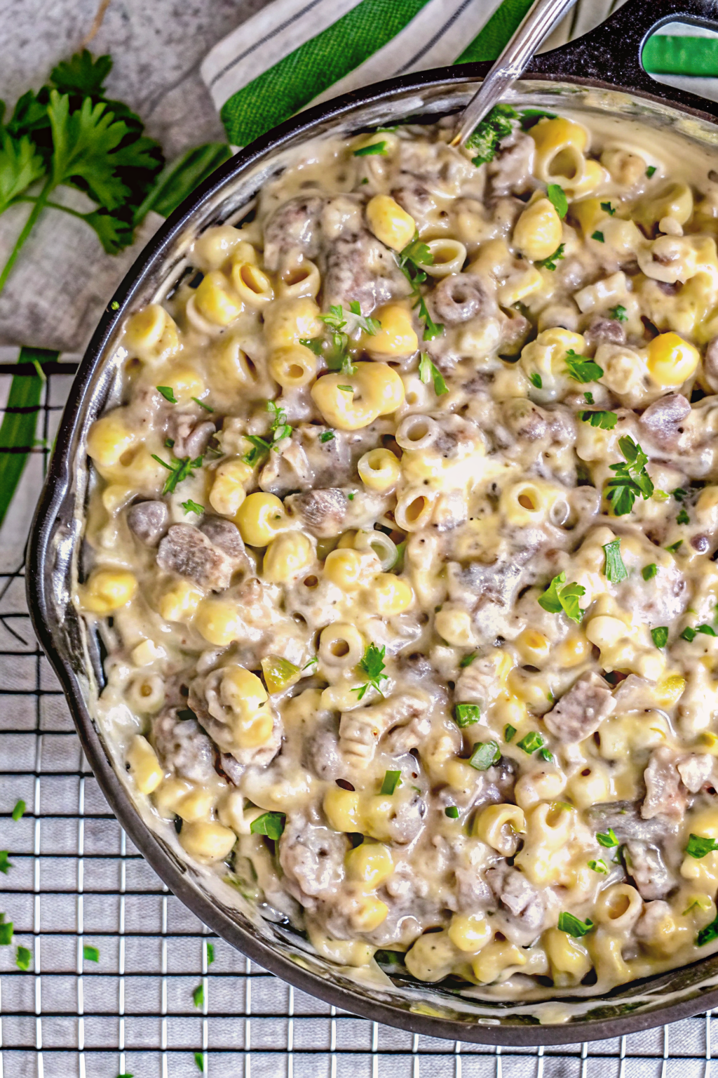 Cheesesteak mac and cheese in a skillet topped with melted cheese