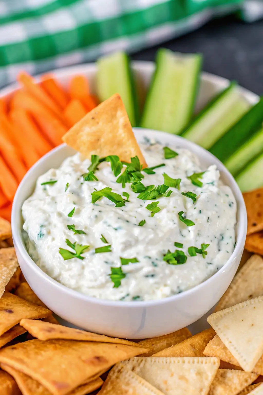 Bowl of creamy chip dip with sour cream surrounded by potato chips