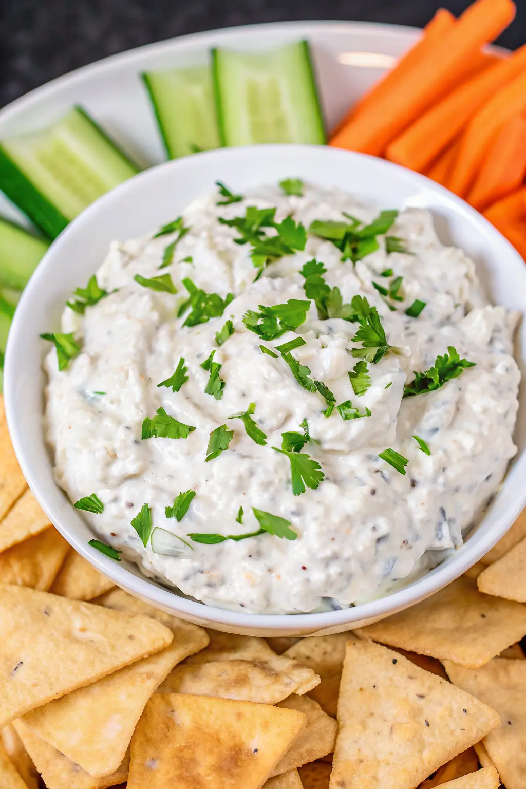 Finished chip dip with sour cream served with chips and herbs