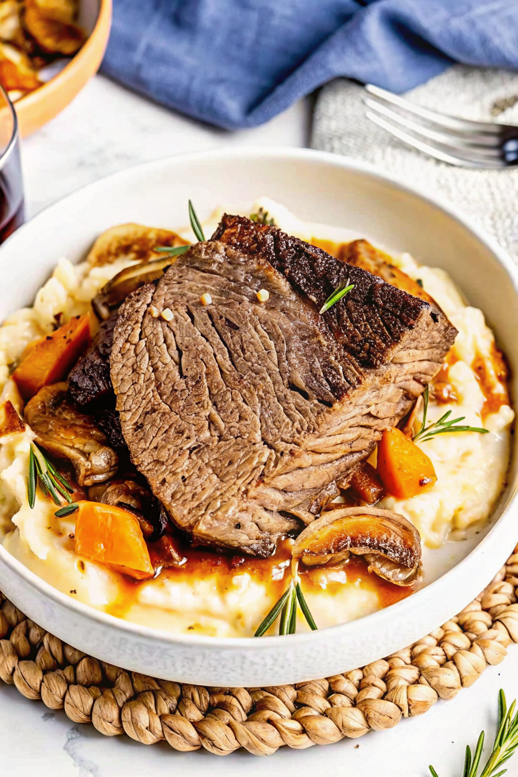 A French dip sandwich piled with roast beef being dipped into a bowl of savory au jus.