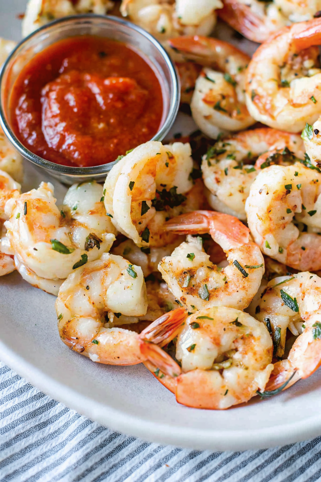 A chilled glass coupe filled with jumbo shrimp and cocktail sauce.