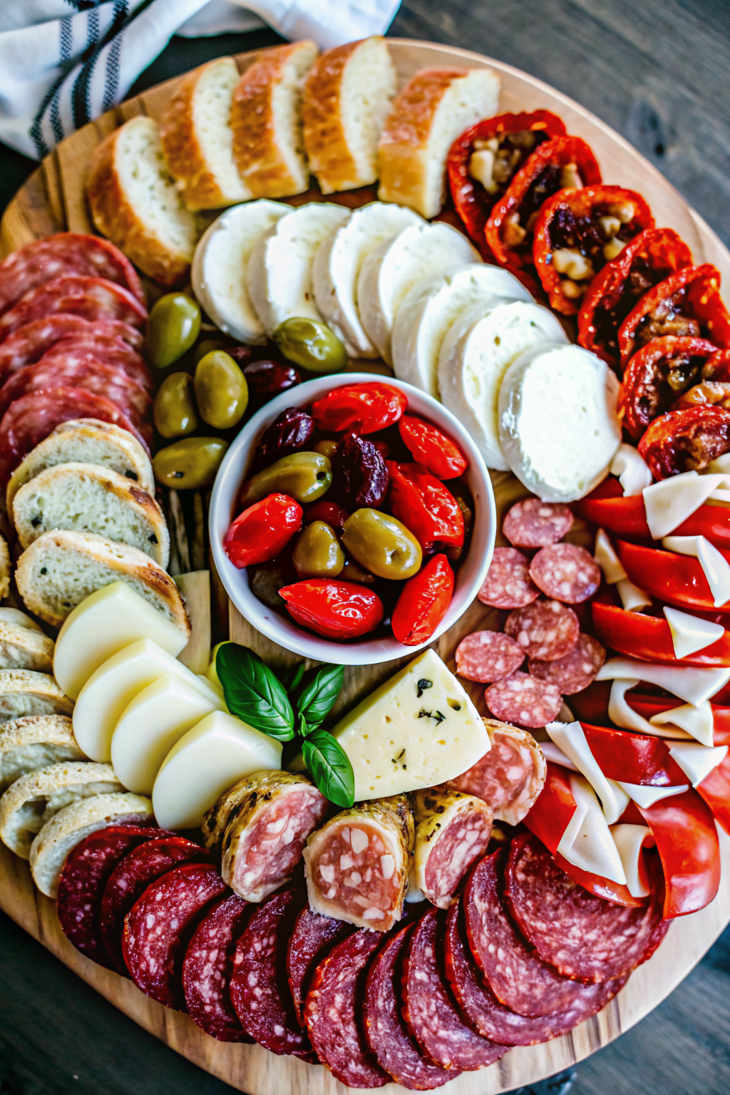 A fully loaded wooden charcuterie board filled with meats, cheeses, and fresh fruit.
