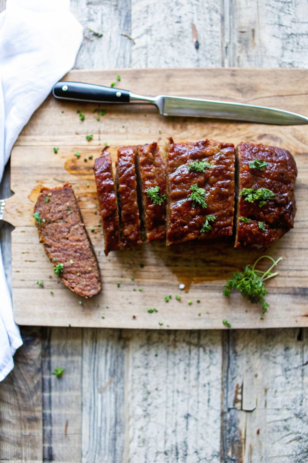 A whole, perfectly glazed, free-form ultimate meatloaf recipe sitting on a wooden board.
