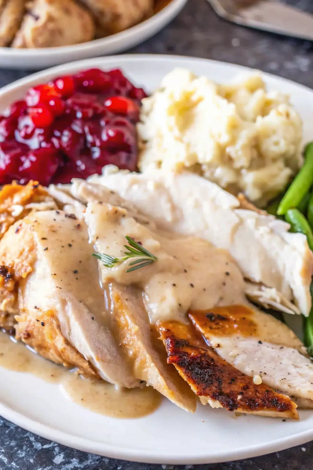 Sliced roasted turkey breast arranged on a platter with herbs.