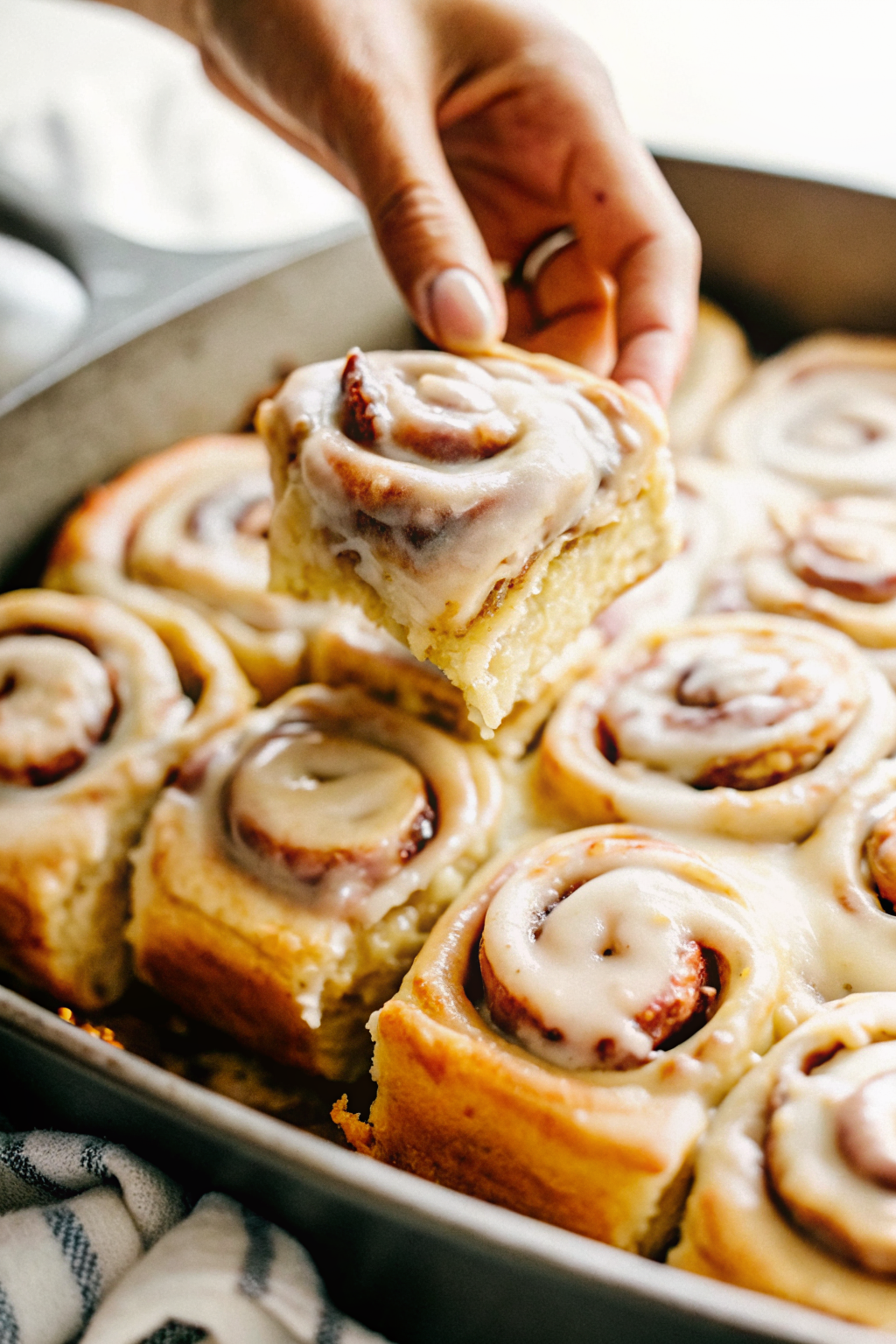 A log of raw dough with cinnamon filling being sliced into rounds on a floured counter.