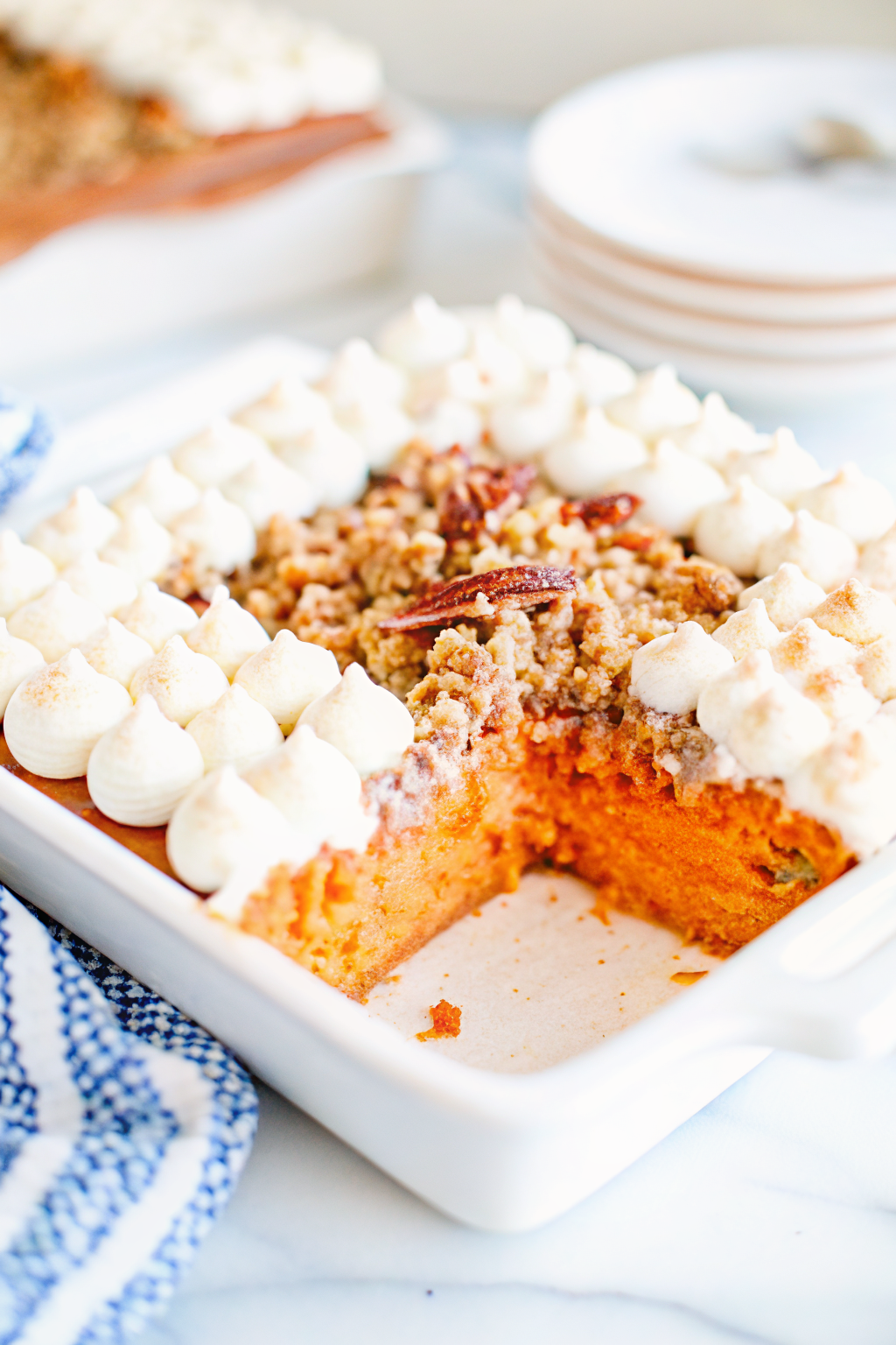 Golden sweet potato casserole with toasted marshmallows and pecans in a ceramic dish