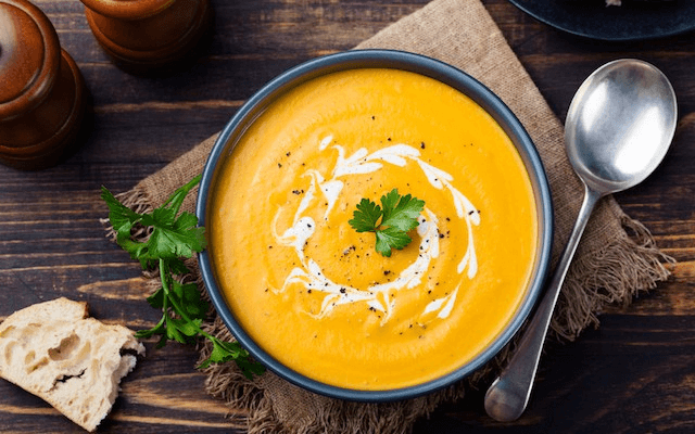Cheesy Pumpkin Potato Leek Soup served in a bowl with cheese and herbs