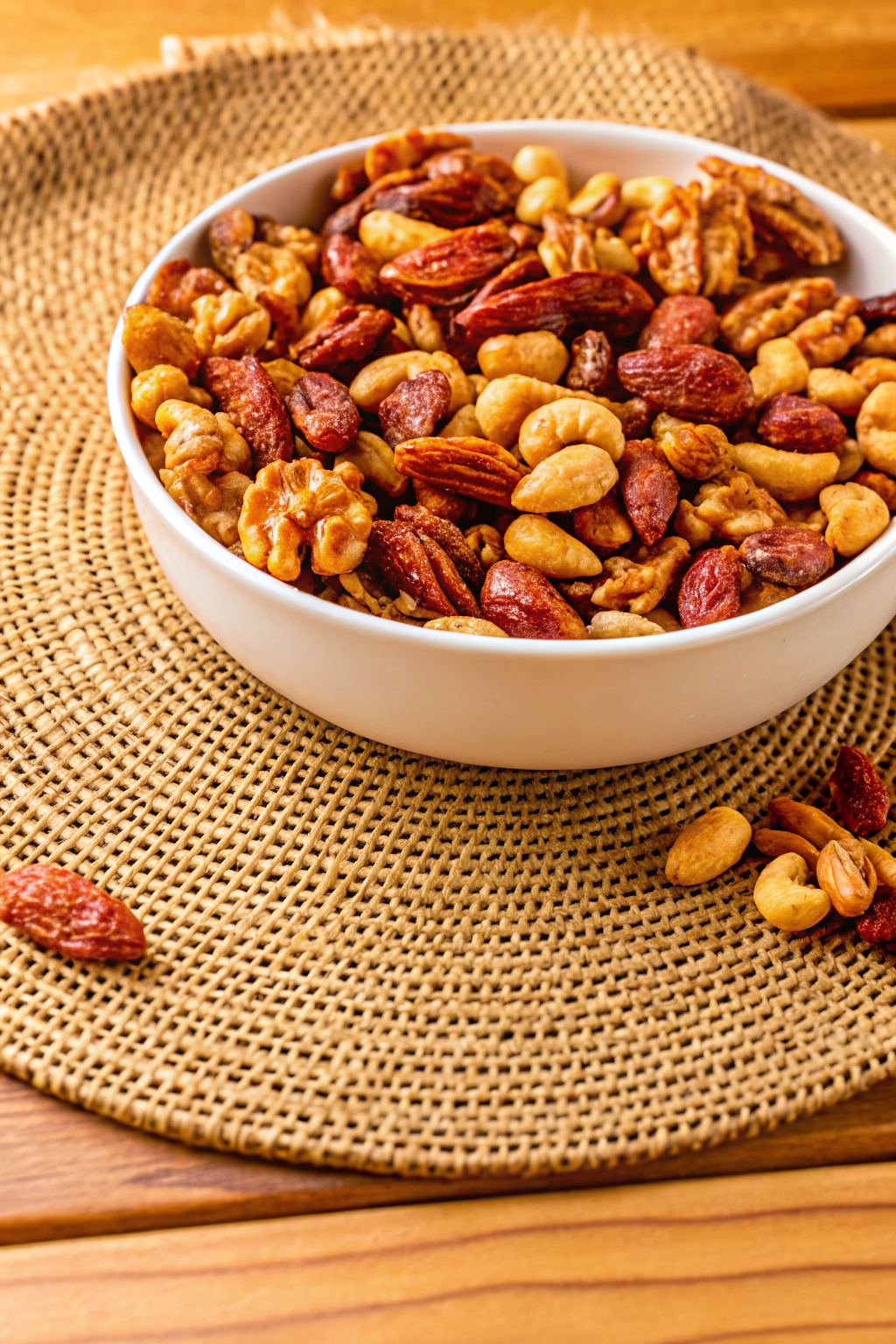 A rustic wooden bowl filled with golden roasted salted mixed nuts including cashews, almonds, and pecans