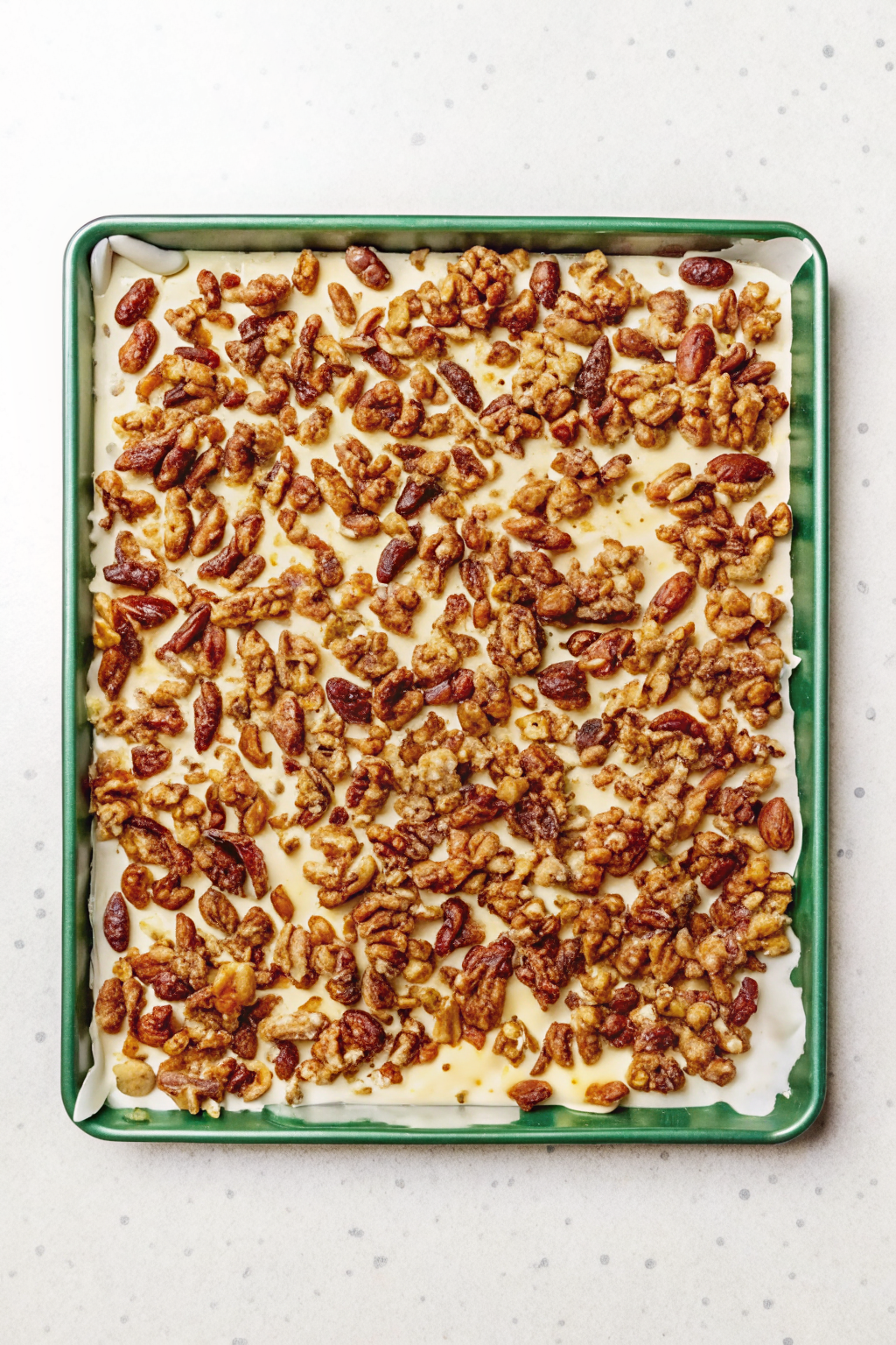 A whisk whipping egg whites in a bowl next to raw nuts and spices