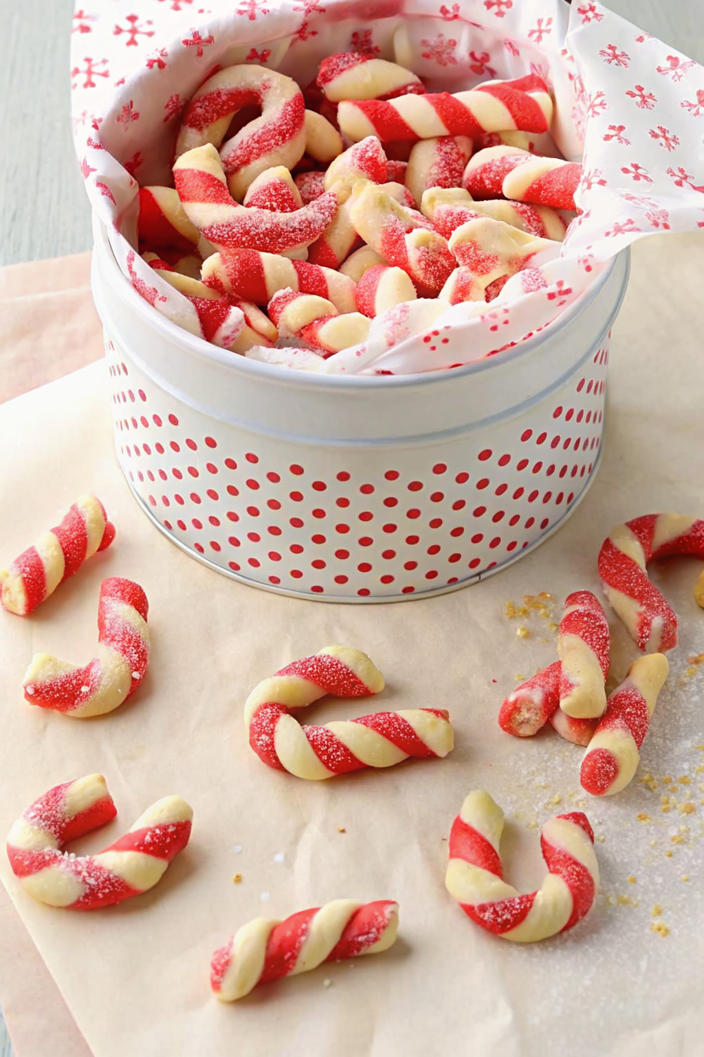 Candy cane cookies dipped in chocolate next to a mug of hot cocoa