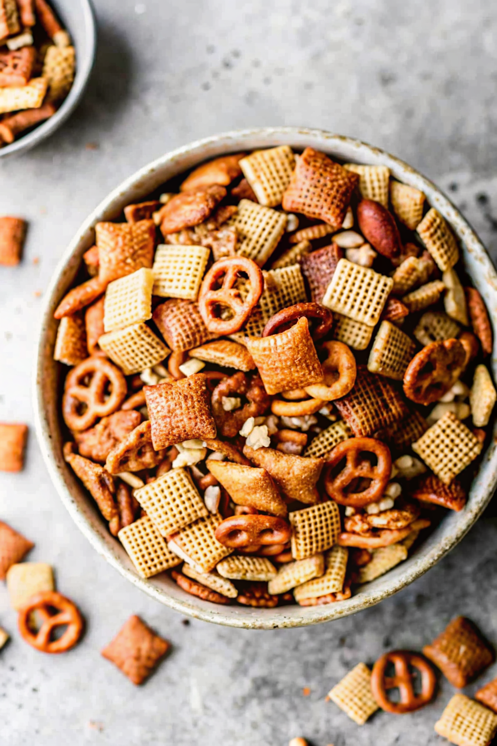 A baking sheet lined with parchment paper covered in roasted snack mix cooling on a counter.