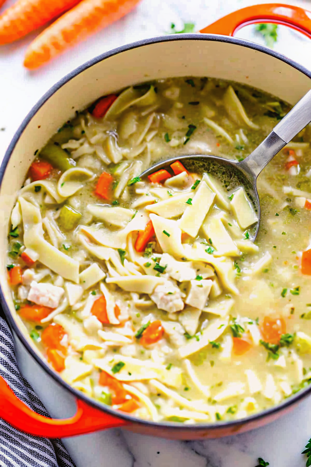A steaming bowl of homemade chicken noodle soup with fresh parsley on a wooden table