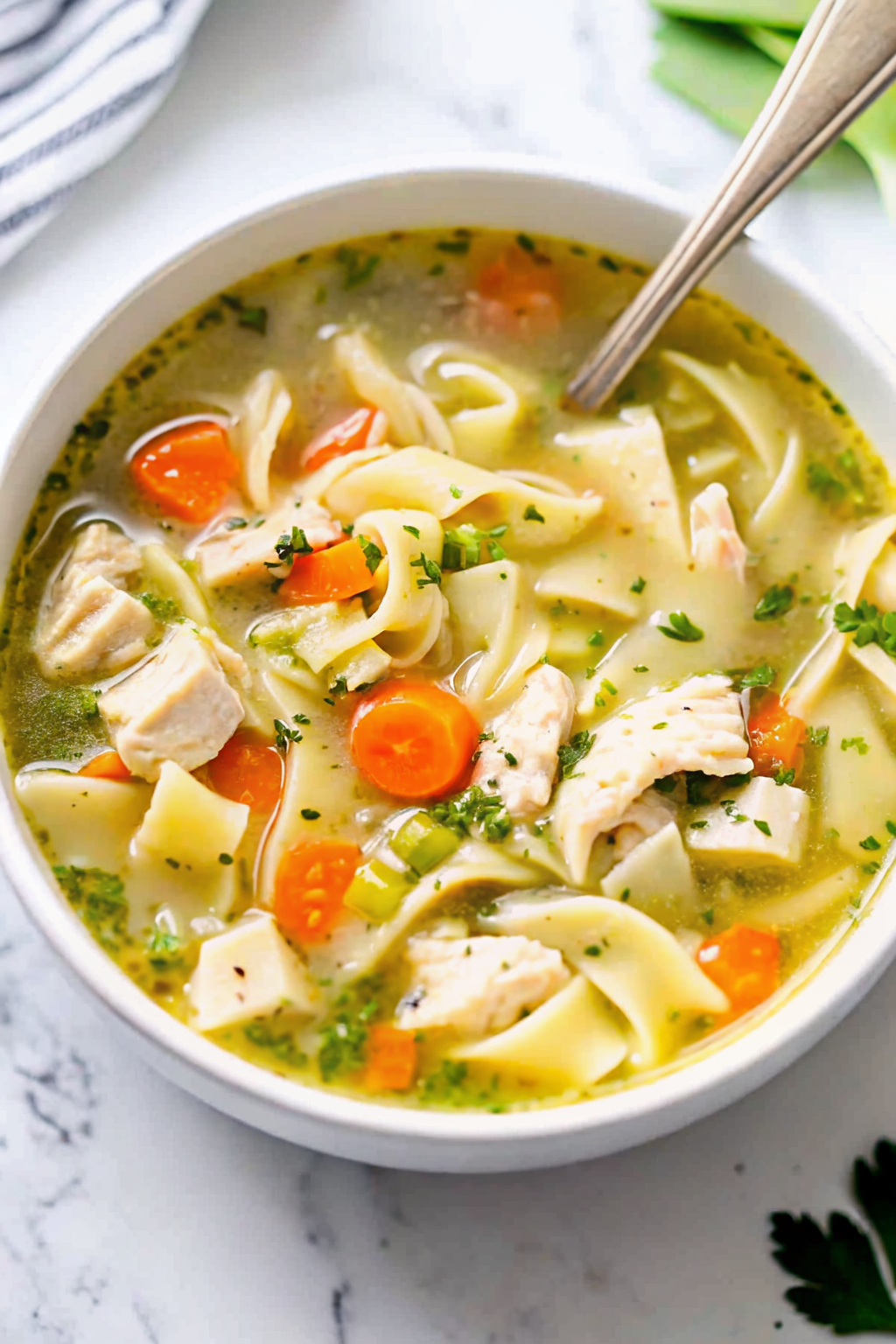 A spoonful of hot chicken noodle soup served with crusty bread in a cozy setting