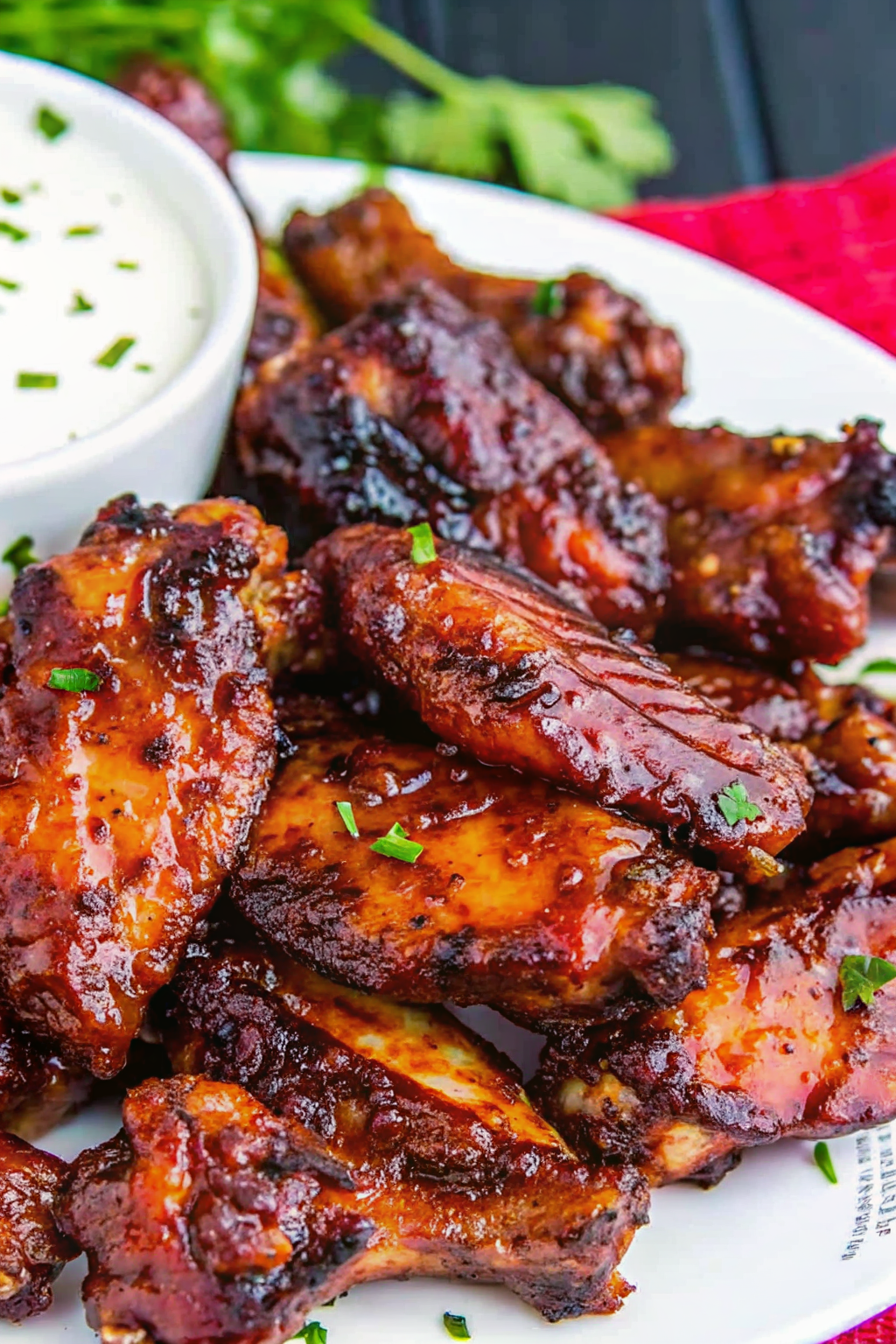 Crispy wings being tossed in a metal bowl with rich BBQ sauce