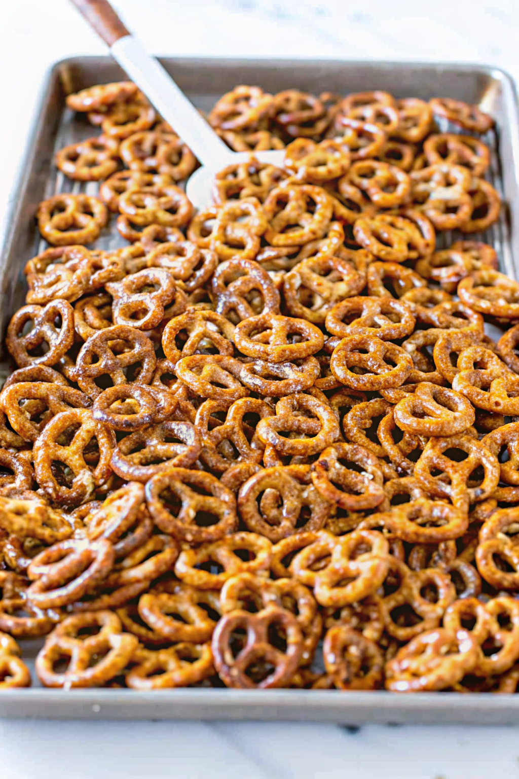 Seasoned pretzels spread out on a baking sheet inside an oven