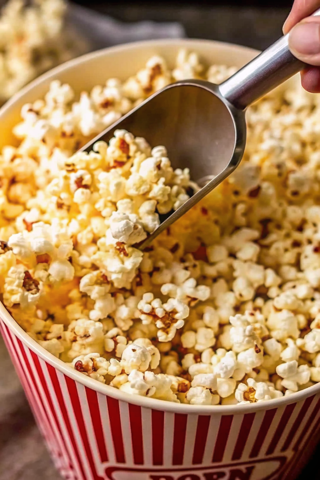 A heavy stainless steel pot on a gas stove with popcorn kernels popping inside