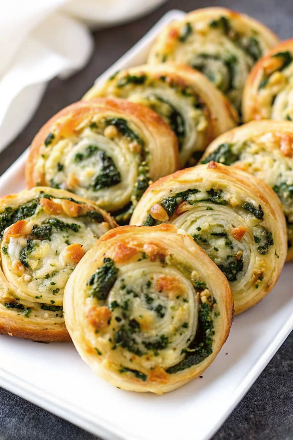 Raw spinach and feta pastry log sliced into spirals before baking.