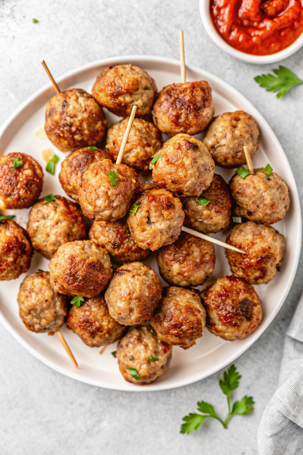Rolling raw meat mixture into uniform mini meatball bites on a wooden board