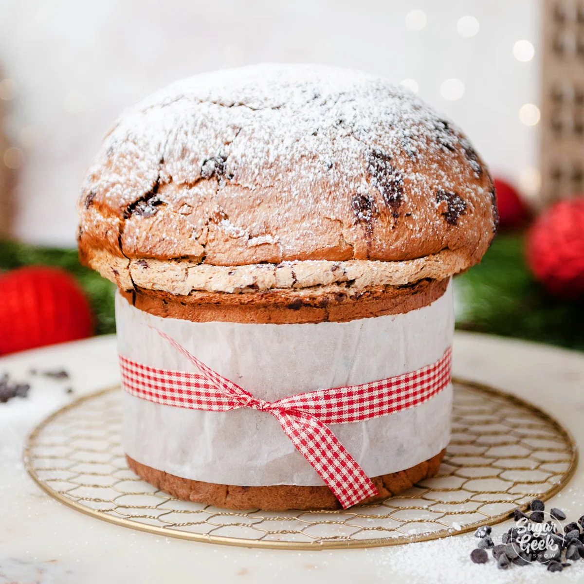 A whole moist Christmas cake topped with glazed cherries and nuts on a wooden table