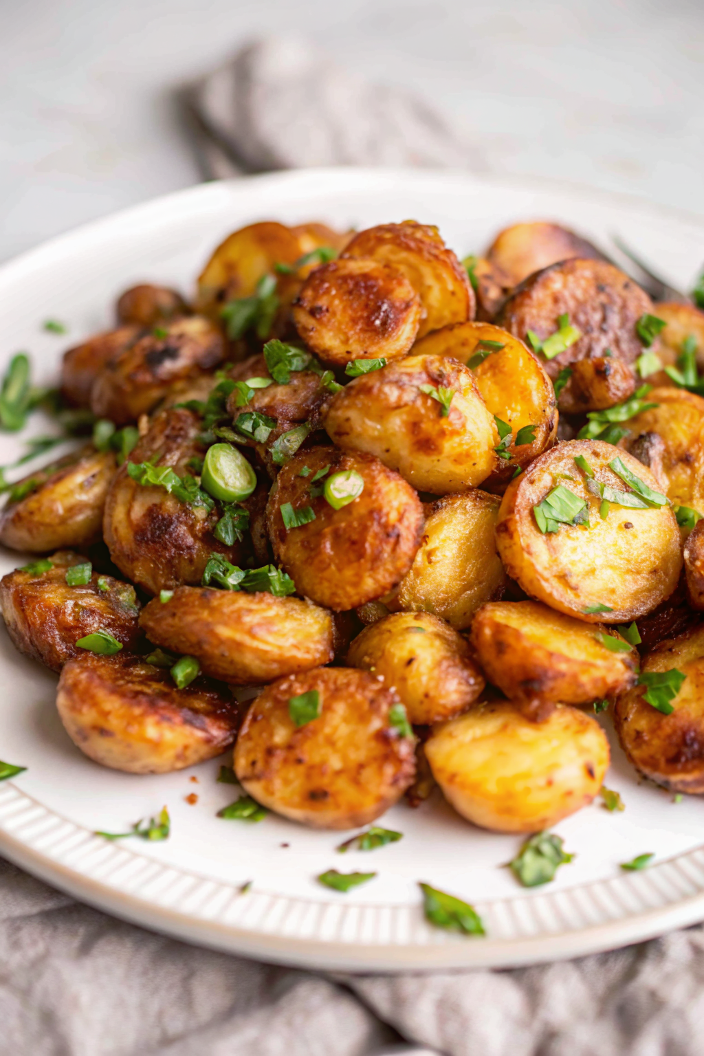 A rustic ceramic bowl filled with golden crispy garlic roasted potatoes garnished with fresh parsley