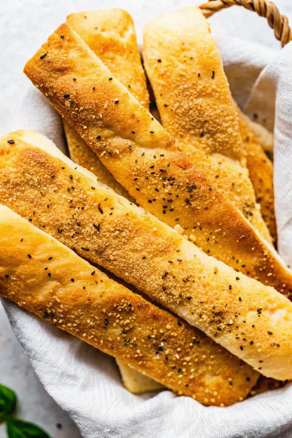 A basket of golden brown garlic parmesan bread sticks brushed with butter.