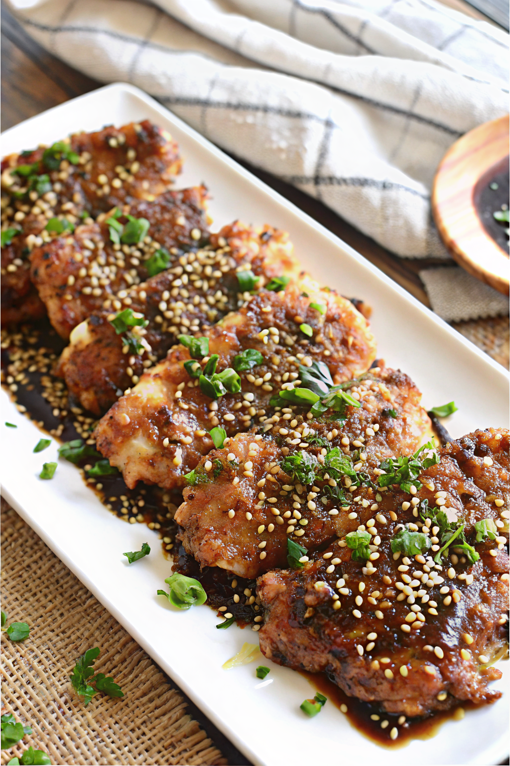 A skillet of sticky Brown Sugar & Soy Glazed Chicken Thighs garnished with green onions