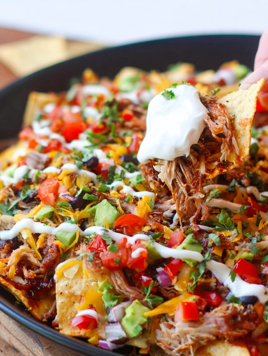 A baking sheet filled with cheesy Instant Pot Pulled Pork Nachos topped with jalapeños and onions