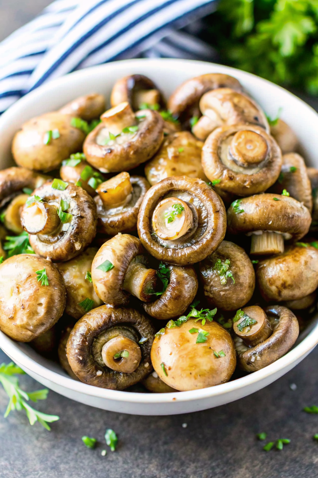 Tossing raw mushrooms with olive oil, garlic, and fresh herbs in a bowl